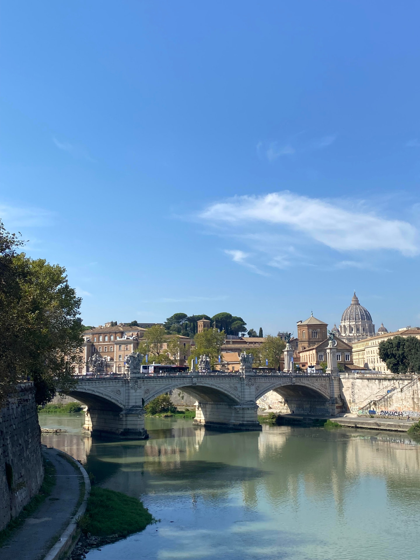 The Tiber river in Rome with a bridge and the dome of St. Peter's Basilica beyond